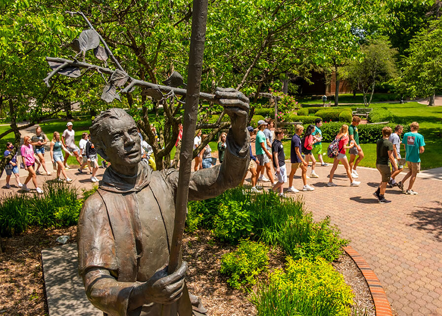 St. Norbert College students walk near a statue of St. Norbert of Xanten.