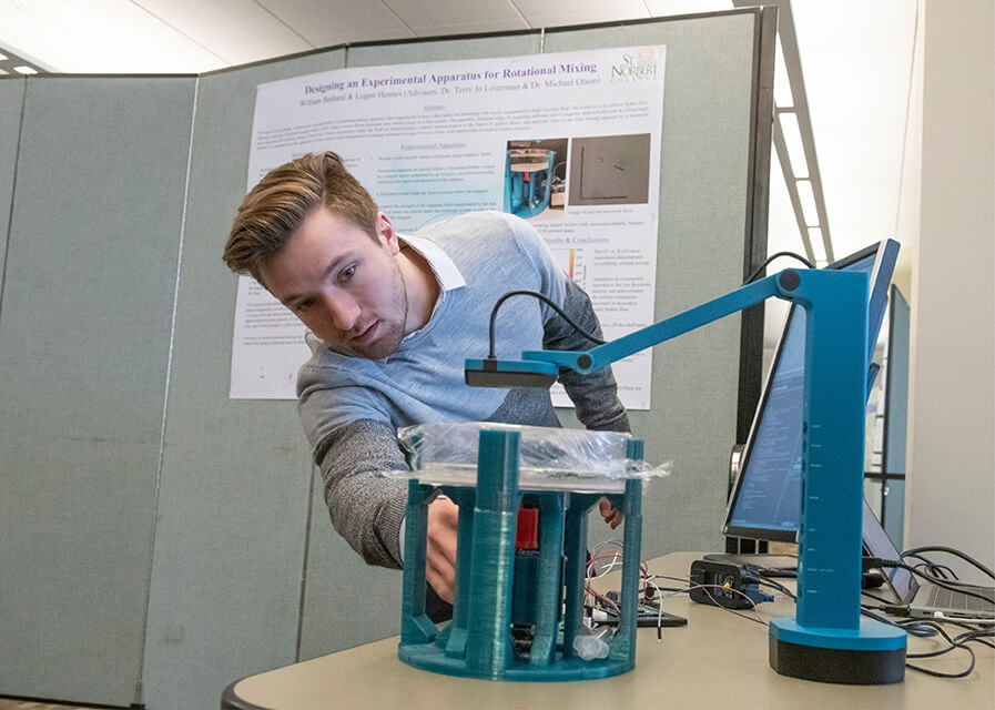 A physics student demonstrates part of a research project.