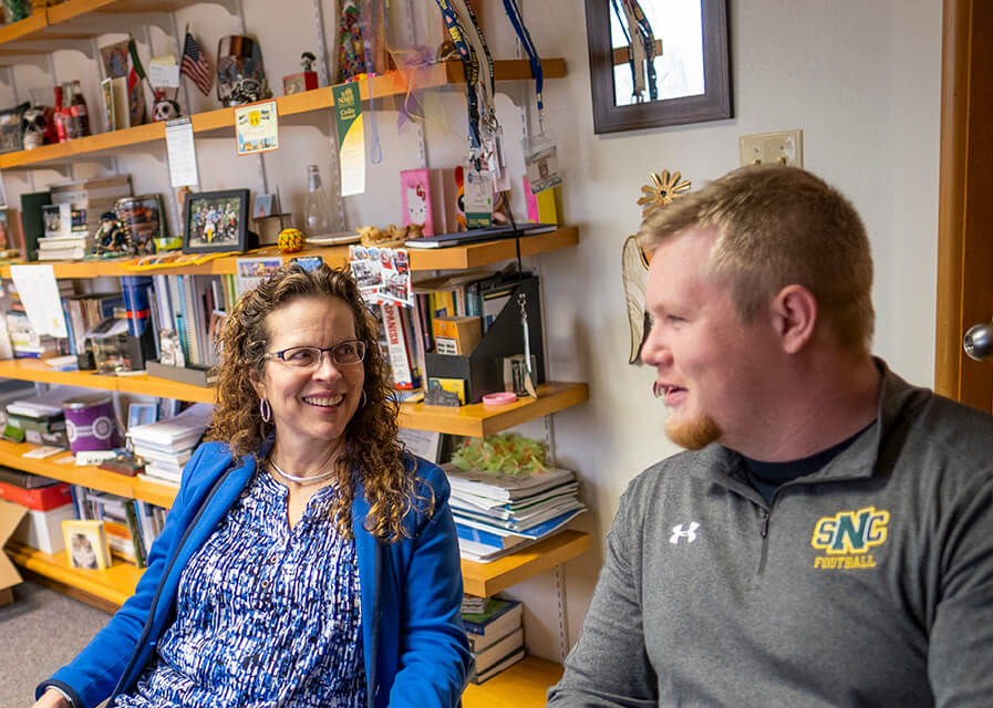 Faculty member speaking with a students in her office.